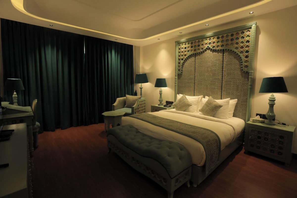 A spacious hotel room with a large bed, two bedside tables, a desk, and a chair.