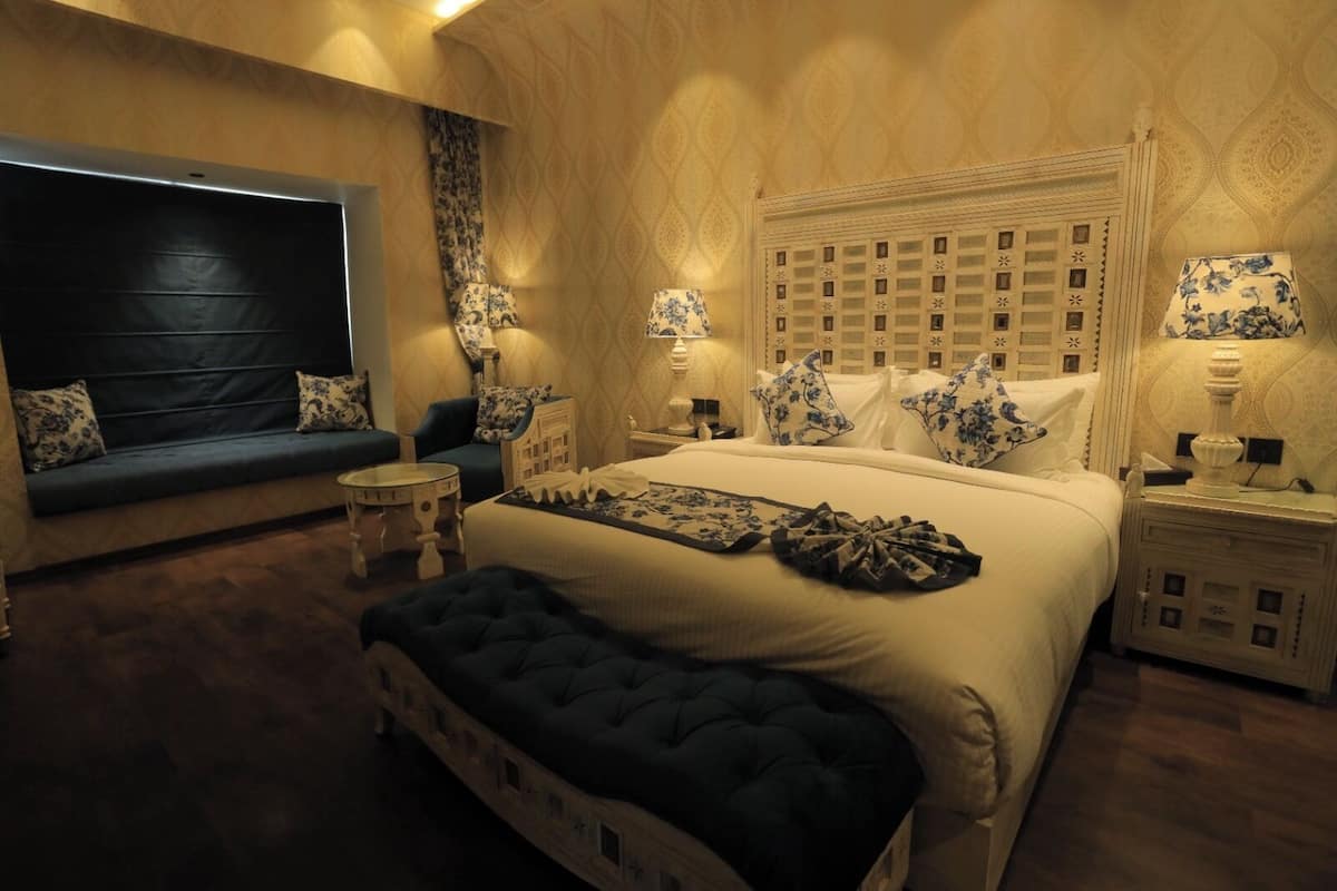 A bedroom with a large bed, a sofa, a small round table, and a nightstand.