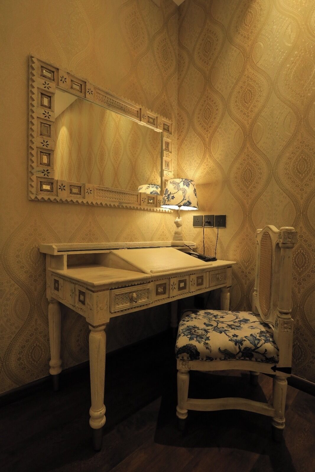 Ein Badezimmer mit Waschtisch, Spiegel, Lampe und Stuhl.