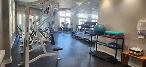 Un gimnasio con diversos equipos de ejercicio, incluyendo cintas de correr, bicicletas estáticas y máquinas de pesas.