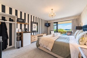 Un dormitorio moderno con una cama grande, un escritorio, un televisor y vistas al exterior.