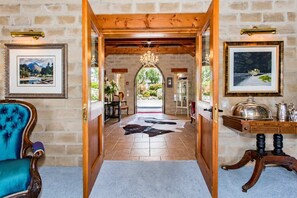 Un hall d’hôtel avec un mur en pierre, un plafond en bois, un lustre, un coin repas avec une table et des chaises, et un comptoir de réception.