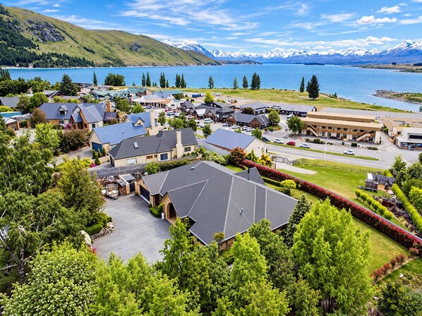 A residential area with houses, a parking lot, and a view of a lake and mountains.