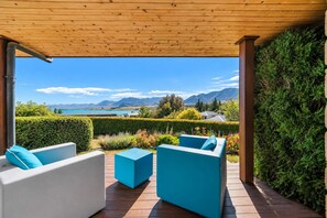 Un espacio de estar al aire libre cubierto con vistas a montañas y un lago.