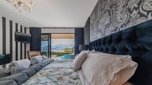 Hotelkamer met een groot bed, een flatscreen televisie, uitzicht op de bergen en een kamer met een patroon op de muur.