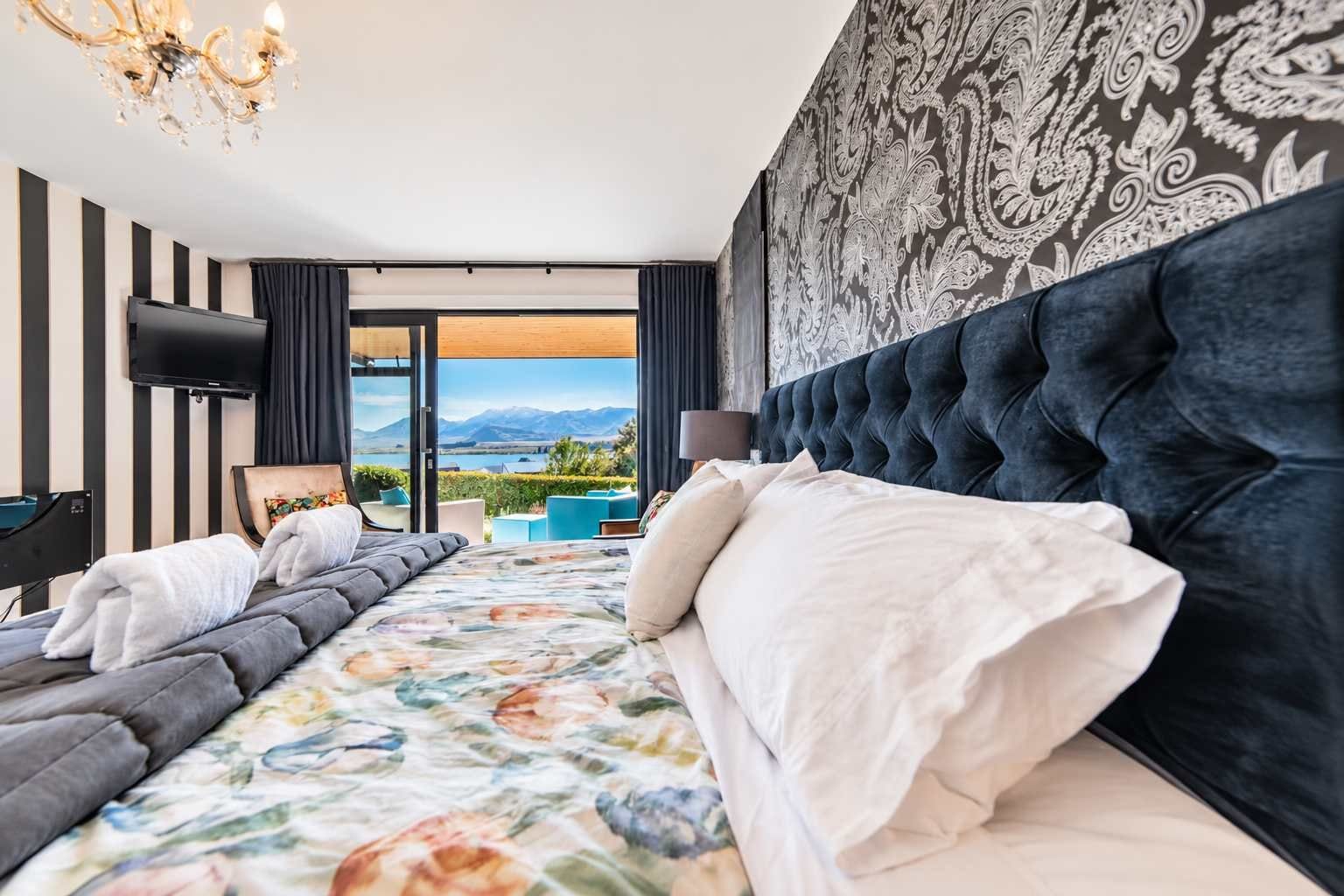 Ein modernes Hotelzimmer mit einem großen Bett, einem Fernseher und Blick ins Freie.