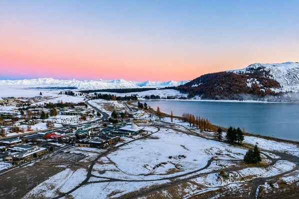 A town with a lake, snow-covered mountains, and a mix of residential and commercial buildings.