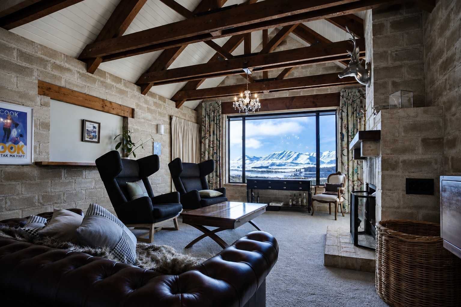 A cozy living room with a fireplace, leather sofa, and a view of mountains.