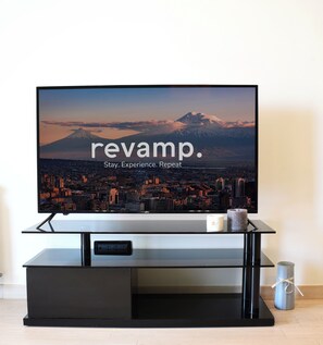A flat-screen TV on a black stand with a cityscape and a mountain in the background.