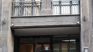 Ein Gebäude mit einem Doppelbalkon, großen Fenstern und einer Tür mit einem Schild.
