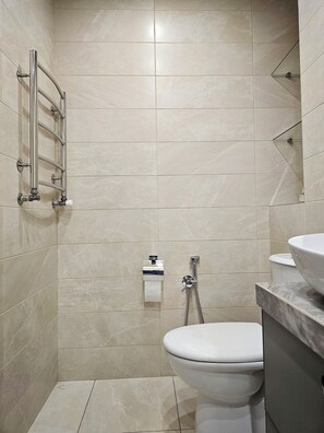 A bathroom with a toilet, a shower, and a towel rack.