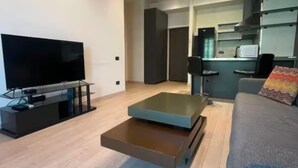 Ein modernes Wohnzimmer mit Flachbildfernseher, einer Couch und einem Couchtisch.
