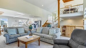 A spacious living room with a sofa set, a coffee table, and a staircase leading to an upper level. - Little, Ships Watch Community in Duck, NC (Kitty Hawk)