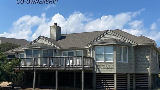 A two-story house with a balcony, a chimney, and a large window. - Shabedge, Ships Watch Community in Duck, NC (Kitty Hawk)