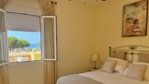 Un dormitorio con cama, mesita de noche, lámpara y un cuadro en la pared.