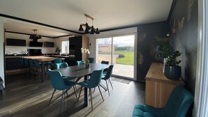 Eine moderne Küche mit Essbereich, einem großen Tisch und Stühlen sowie Blick ins Freie.