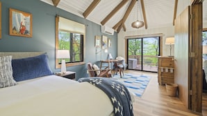 Ein Schlafzimmer mit Bett, Schreibtisch, Stuhl und Blick ins Freie.