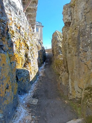 A narrow stone pathway flanked by weathered walls with moss and lichen growth.