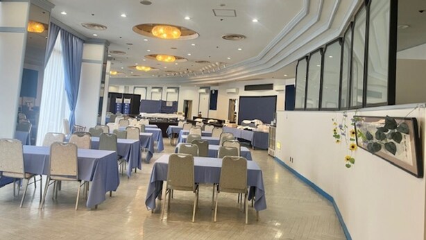 A conference room with round tables, chairs, and a large screen. - Hotel Tetora Resort Shizuoka Yaizu (Yaizu)