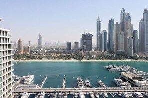 A marina with numerous yachts docked, a city skyline with modern skyscrapers, and a clear view of the water. - 2B Beachfront with Harbour Views and  Beach Access (Dubai)