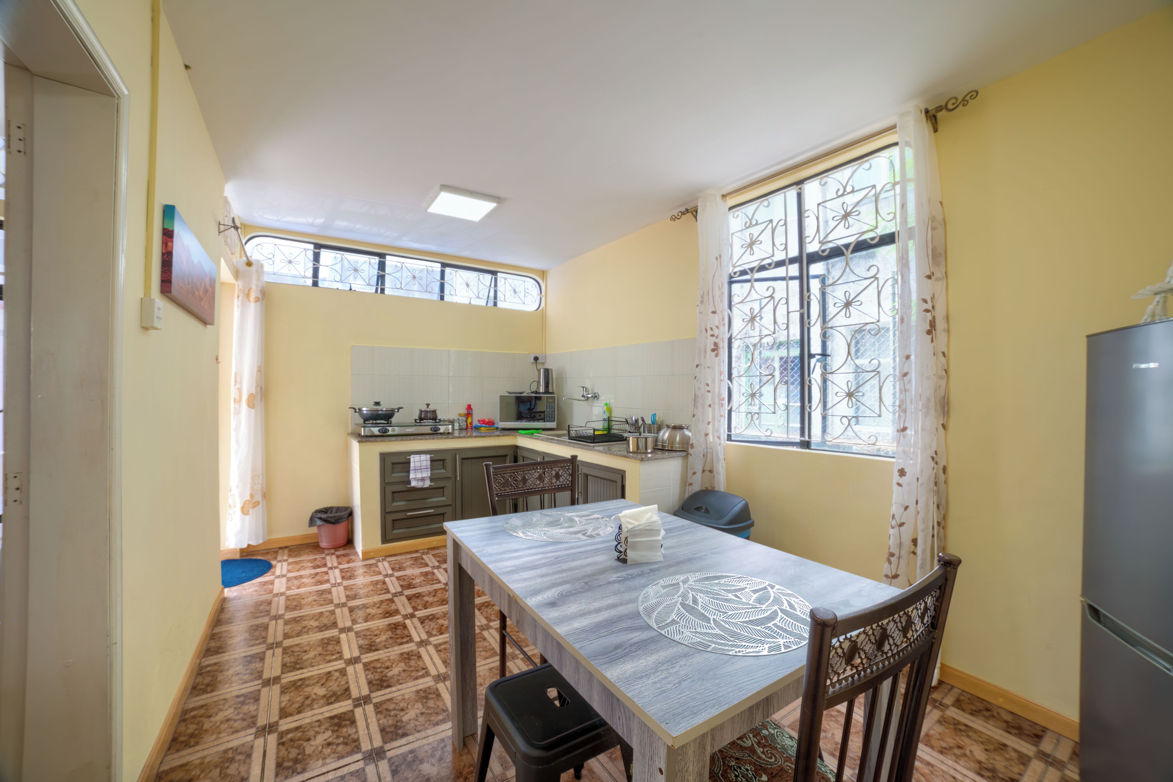 A compact kitchen with a dining table, chairs, and a refrigerator.