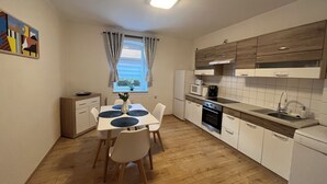 A compact kitchen with a dining area, wooden cabinets, a microwave, and a view of the sea through a window.