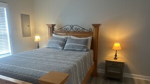 A bedroom with a bed, nightstand, lamp, and a window with blinds. - 2BR The Bandit Suite (Lexington)