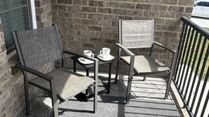 A balcony with two chairs, a small table, and two white cups. - 2BR The Bandit Suite (Lexington)