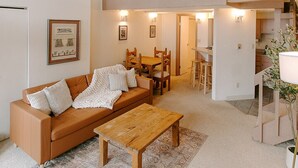 A spacious living area with a high ceiling, a wooden dining table, and a sofa. - Budget Ski-In/Out+Walk to Dining (Steamboat Springs)