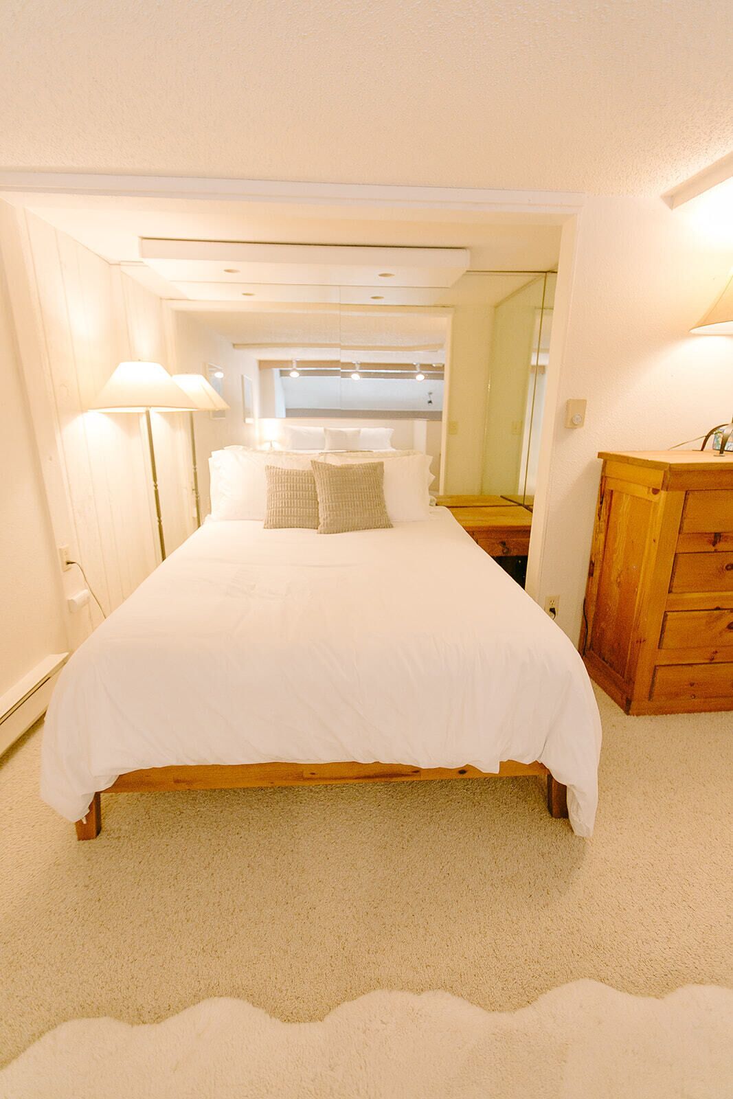 A bedroom with a large bed, a wooden dresser, and a nightstand.