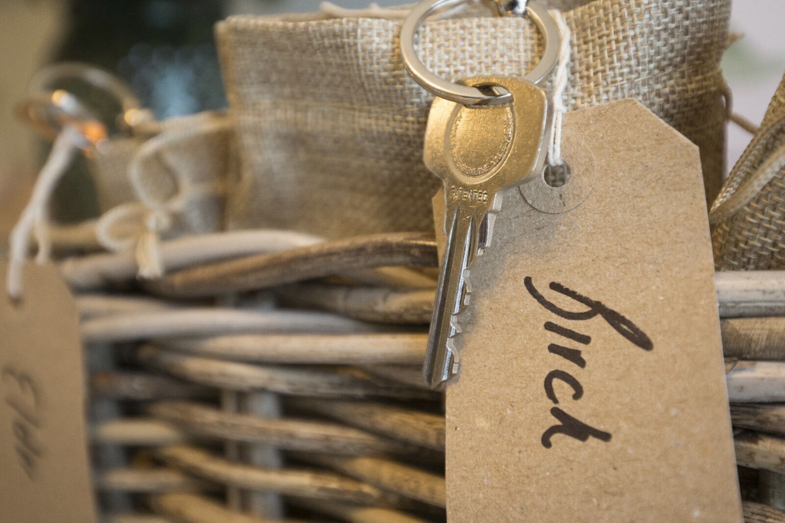 Un panier en osier contenant des clés et des étiquettes en métal, dont l’une porte l’inscription « Bouleau ».