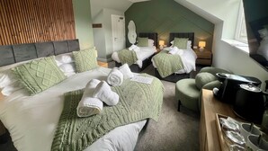 Ein Hotelzimmer mit zwei Betten, einem Fernseher, einem Wasserkocher und einem Essbereich.