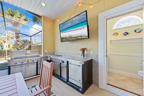 A kitchen with a built-in grill, a sink, and a window overlooking a beach.