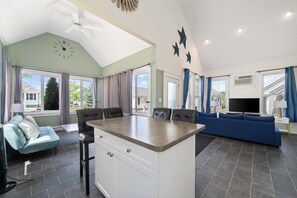 Un vaste espace de vie comprenant un îlot de cuisine, un canapé bleu et une table à manger avec des chaises.