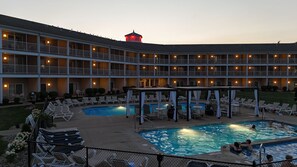 A hotel with multiple balconies, outdoor pools, and lounge chairs.