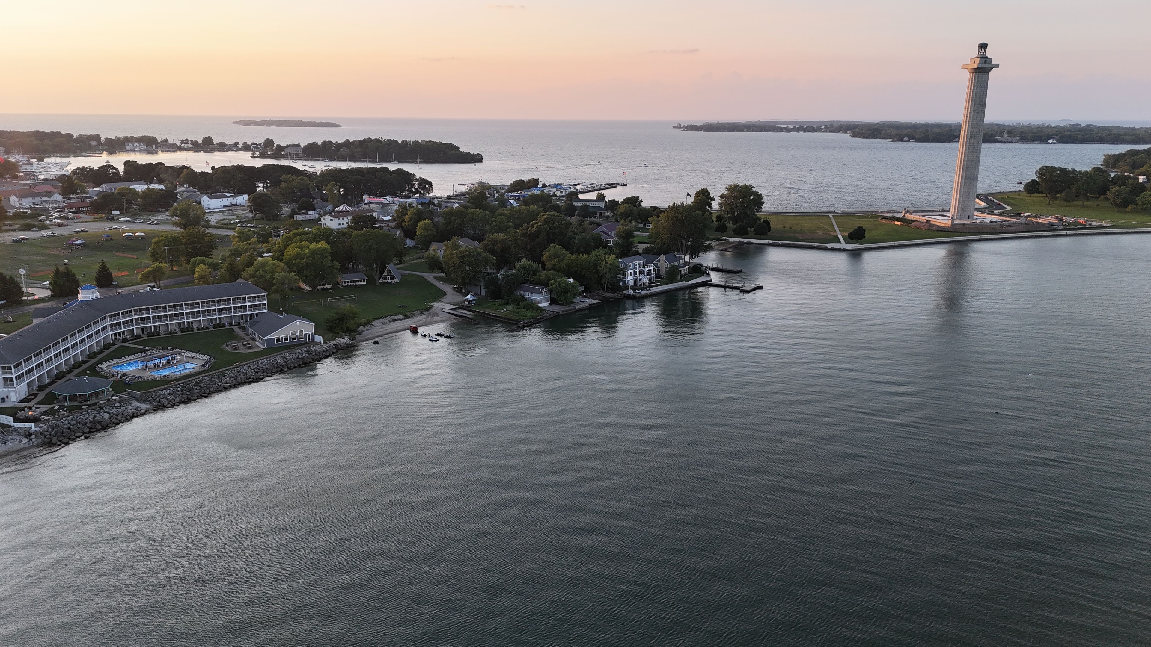 A waterfront property with a lighthouse, a swimming pool, and a large building with a curved roof.
