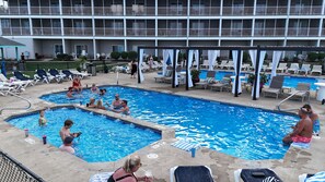 Un espace piscine comprenant plusieurs piscines, des chaises longues et des parasols.