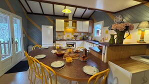 A kitchen with a round dining table, yellow chairs, and a variety of appliances and utensils. - Domme Gite with pool sleeps 8 (Domme)