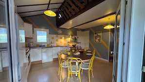 A modern kitchen with white cabinets, a dining area with yellow chairs, and a staircase. - Domme Gite with pool sleeps 8 (Domme)