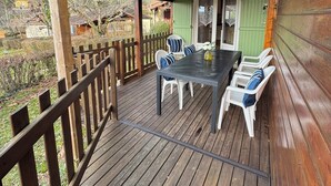 A wooden deck with a table and chairs, a covered area, and a view of the surrounding landscape. - Domme Gite with pool sleeps 8 (Domme)