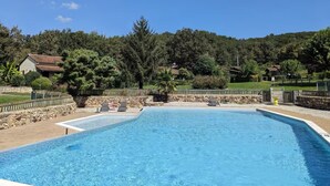 A rectangular swimming pool with a stone border, surrounded by a stone wall and a wooden fence. - Domme Gite with pool sleeps 8 (Domme)