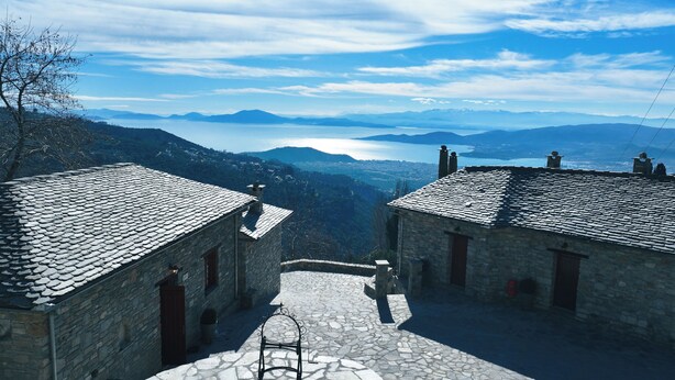 A stone building with a tiled roof overlooking a valley and mountains. - AURORA-INN (Volos)
