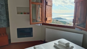 A room with a wooden cabinet, a radiator, and a window with a view of a landscape. - AURORA-INN (Volos)