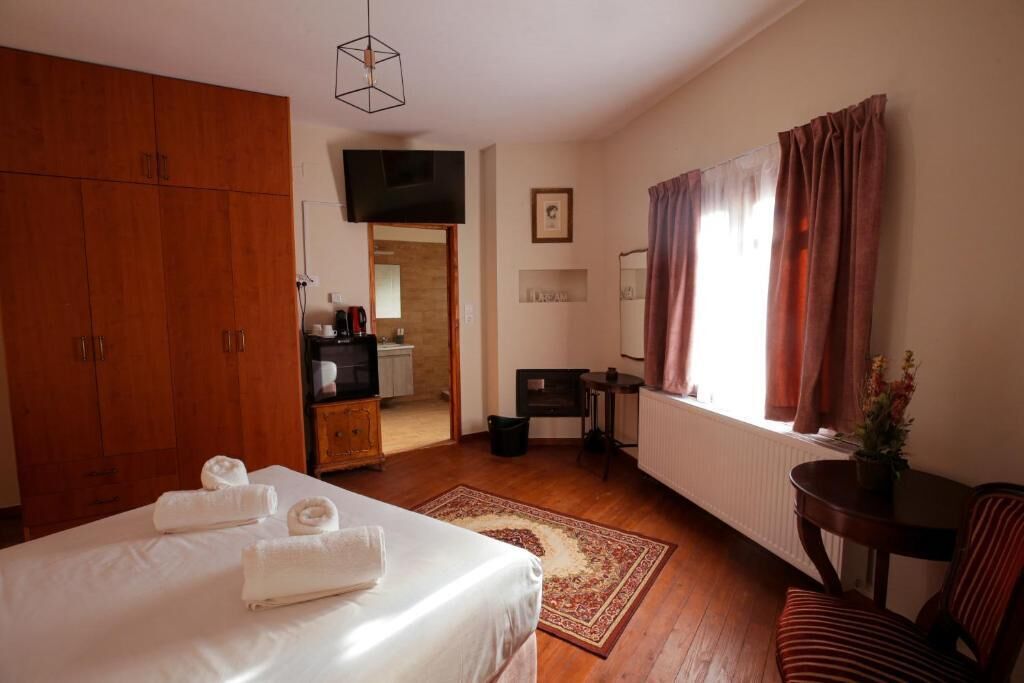 Un dormitorio con cama, armario de madera, escritorio, silla, radiador y ventana con cortinas.