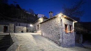 A stone building with a small window and a door, surrounded by a stone pathway. - AURORA-INN (Volos)