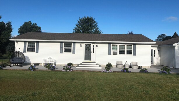 A single-story house with a front porch, a small front yard, and a clear blue sky. - Charming 3-bedroom house in wonderful Sackets Harbor with WiFi, AC (Sackets Harbor)
