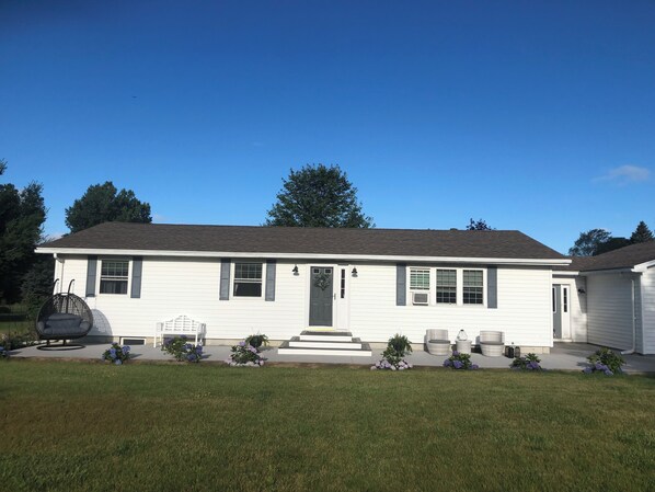 A single-story house with a front porch, a small front yard, and a clear blue sky. - Charming 3-bedroom house in wonderful Sackets Harbor with WiFi, AC (Sackets Harbor)