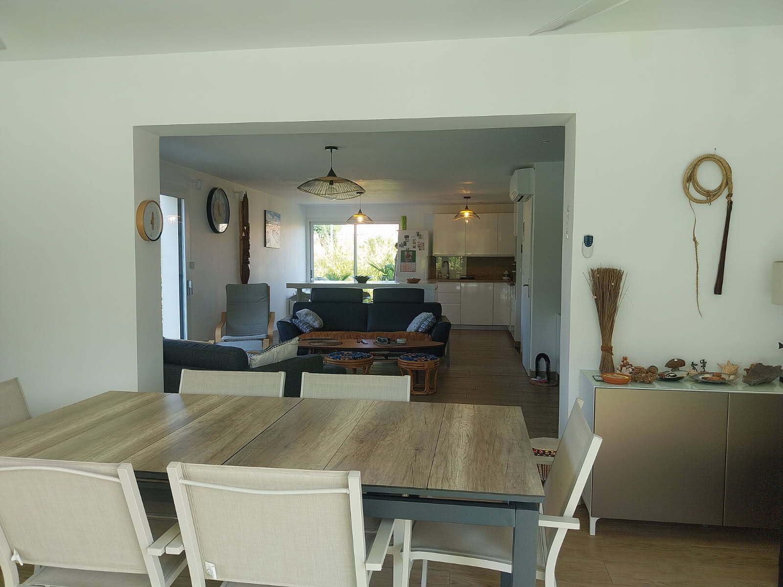 Een moderne woonkamer met een eettafel, banken en een keuken op de achtergrond.