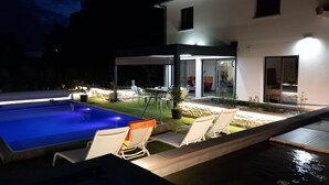 A modern house with a swimming pool, outdoor seating, and a well-lit patio area. - 4CH villa with pergola, swimming pool located 4km from Lac CARCANS and 9km from the Ocean (Carcans)