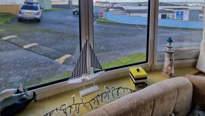 Ett vardagsrum med ett stort fönster med utsikt över en parkeringsplats och en vattenyta.